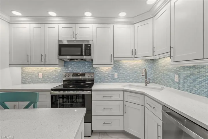 Kitchen featuring appliances with stainless steel finishes, light stone counters, backsplash, light marble finish flooring, and recessed lighting