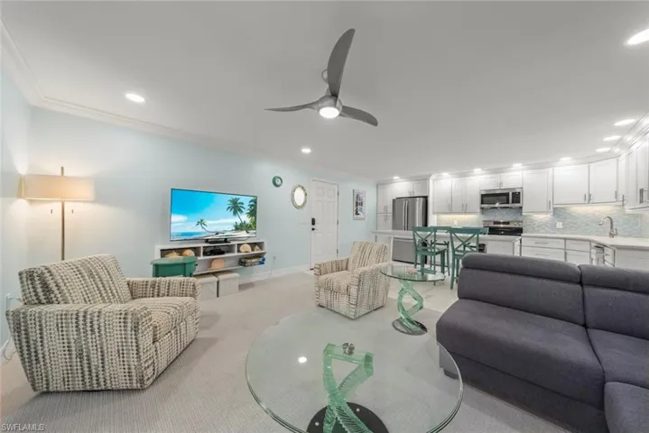 Living area with ornamental molding, recessed lighting, a ceiling fan, and light colored carpet
