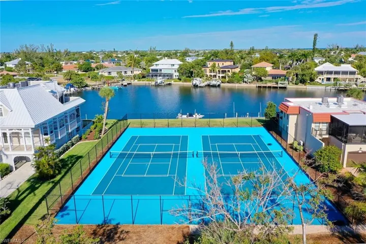View of tennis court featuring a water view, a residential view, and a patio area