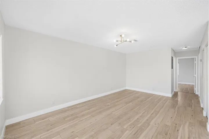 Spare room featuring a notable chandelier, baseboards, and light wood-style floors