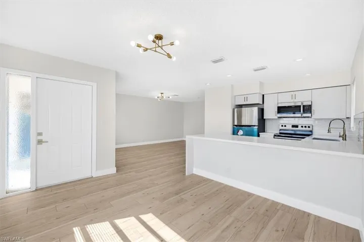 Kitchen with a wealth of natural light, a sink, a chandelier, and appliances with stainless steel finishes