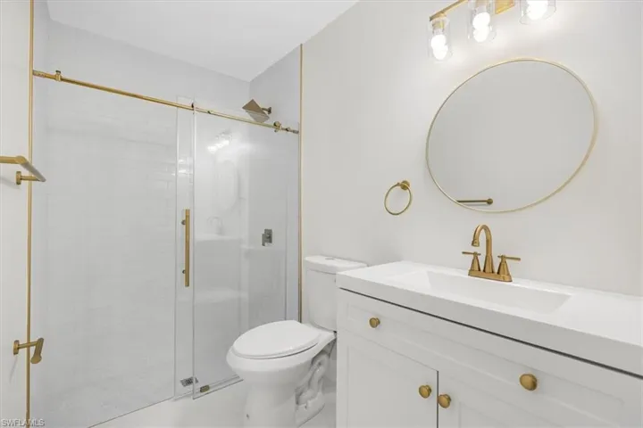 Bathroom featuring toilet, vanity, and a shower stall