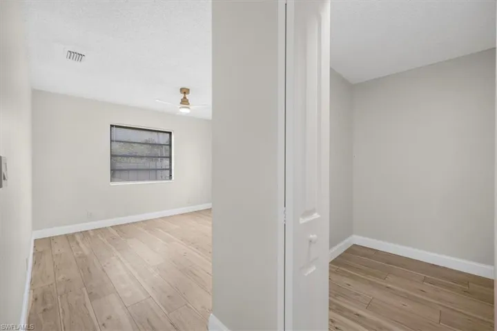 Corridor featuring baseboards, a textured ceiling, visible vents, and wood finished floors