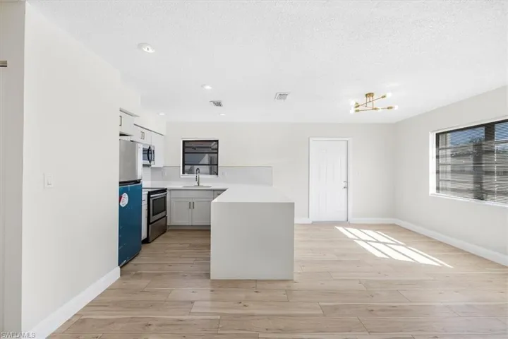 Kitchen featuring light countertops, a sink, light wood finished floors, stainless steel appliances, and visible vents