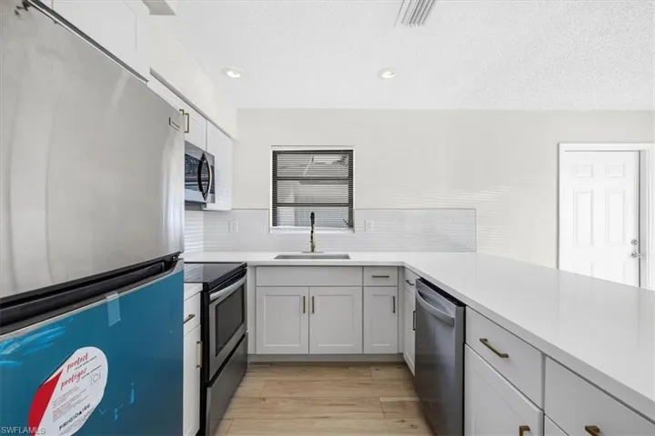 Kitchen featuring a sink, light wood-type flooring, light countertops, and appliances with stainless steel finishes