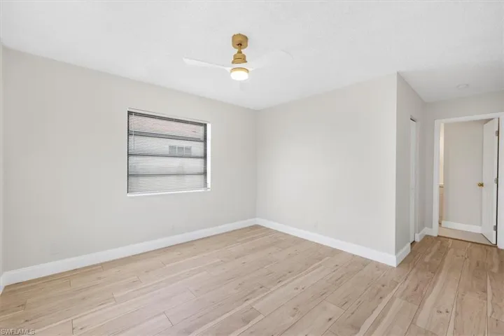 Empty room with baseboards, light wood-style floors, ceiling fan, and a textured ceiling