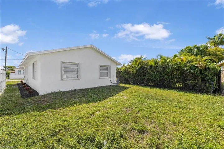 View of home's exterior with stucco siding, fence, and a lawn