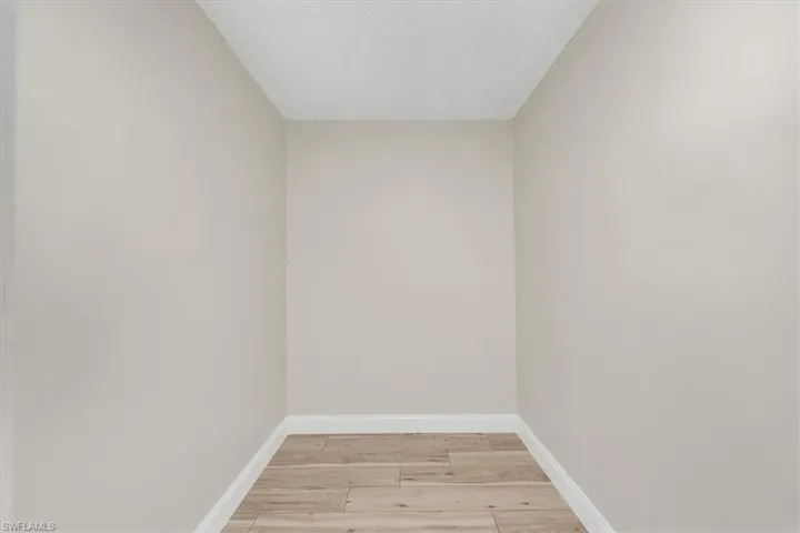 Spare room with baseboards, light wood-style flooring, and a textured ceiling