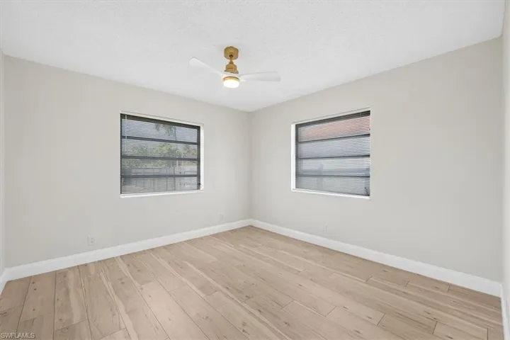 Empty room with baseboards, a textured ceiling, a ceiling fan, and light wood finished floors