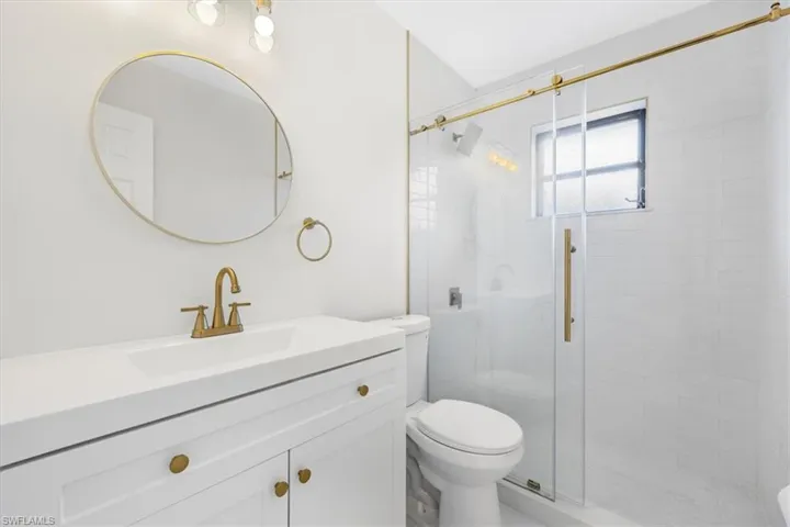 Bathroom featuring a shower stall, toilet, and vanity