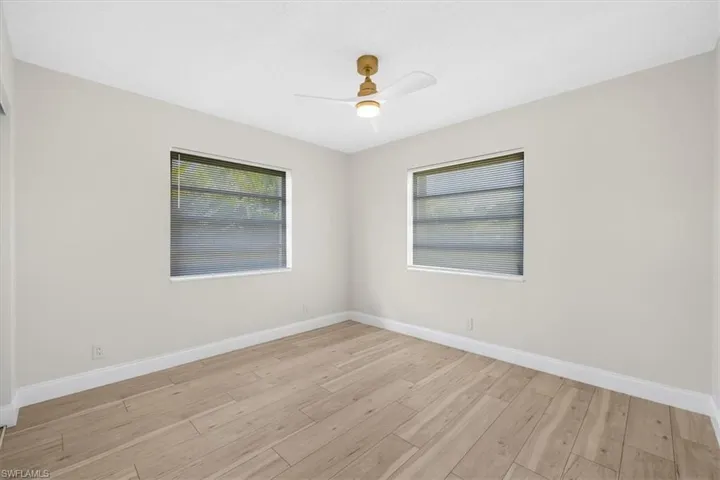Empty room with a ceiling fan, light wood-style flooring, and baseboards