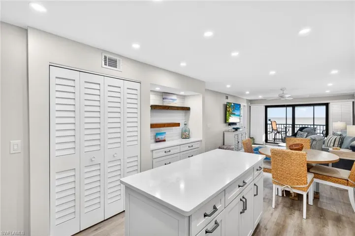 Kitchen featuring open floor plan, a center island, recessed lighting, white cabinets, and light stone countertops