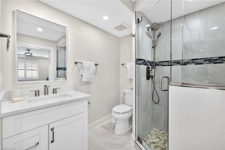 Bathroom featuring vanity, ceiling fan, a stall shower, light marble finish flooring, and recessed lighting