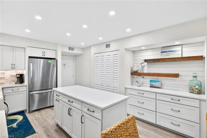 Kitchen featuring freestanding refrigerator, white cabinets, open shelves, a kitchen island, and tasteful backsplash