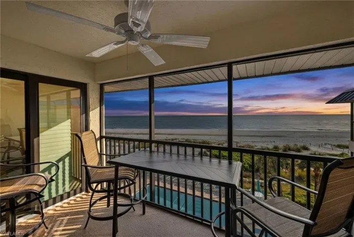 Sunroom / solarium featuring view of water and beach, carpet, and a textured ceiling