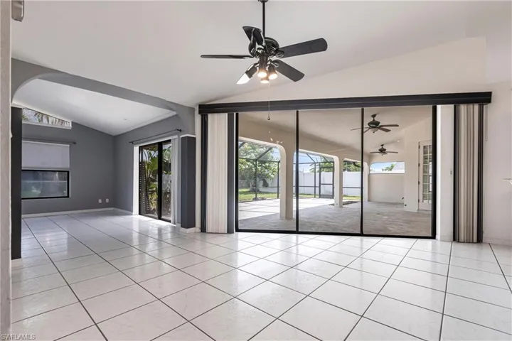 Unfurnished room with vaulted ceiling, tile patterned flooring, a ceiling fan, and arched walkways