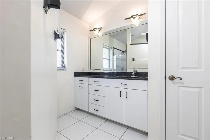 Bathroom featuring lofted ceiling, vanity, a shower, and marble look tile flooring