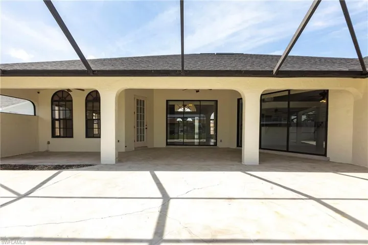 Back of property with glass enclosure, a patio area, and stucco siding