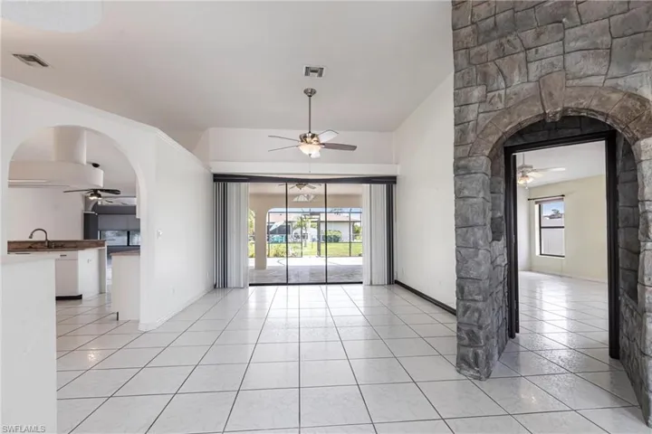 Empty room with ceiling fan, light tile patterned flooring, and healthy amount of natural light
