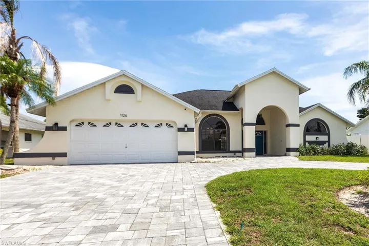 View of front of property with curved driveway, stucco siding, a garage, and a front yard