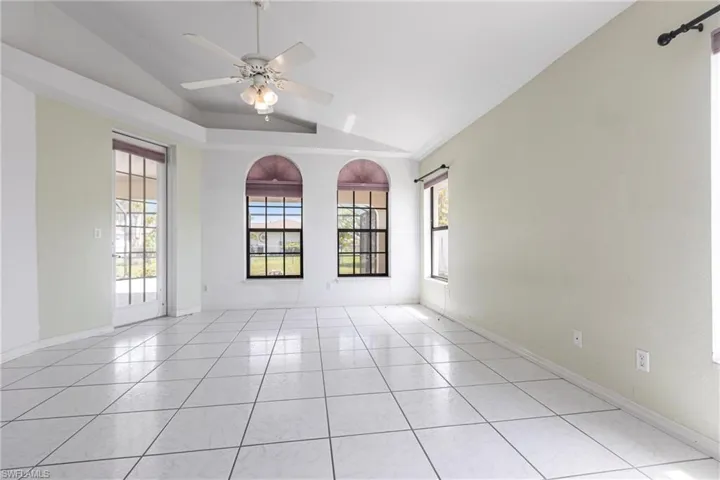 Empty room with lofted ceiling, ceiling fan, and light tile patterned floors