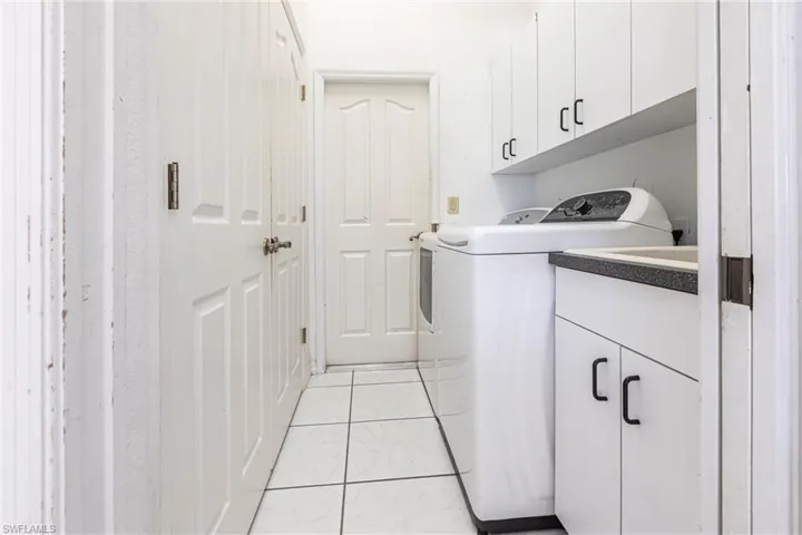 Washroom featuring independent washer and dryer, cabinet space, and light marble finish floors