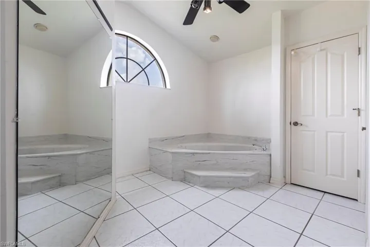 Full bathroom with a garden tub, vaulted ceiling, ceiling fan, and tile patterned flooring