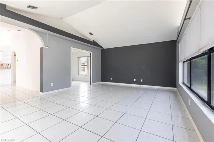 Spare room featuring arched walkways, lofted ceiling, and light tile patterned floors