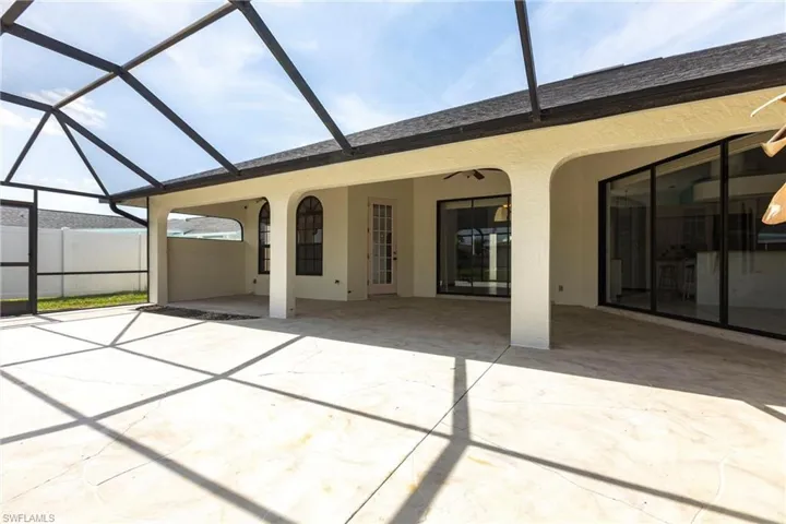 Rear view of house featuring a patio, stucco siding, and glass enclosure