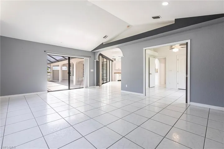Unfurnished room with arched walkways, vaulted ceiling, light tile patterned floors, ceiling fan, and recessed lighting