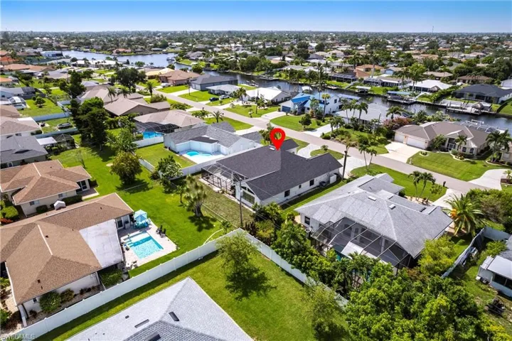 Aerial perspective of suburban area featuring a nearby body of water and a pool