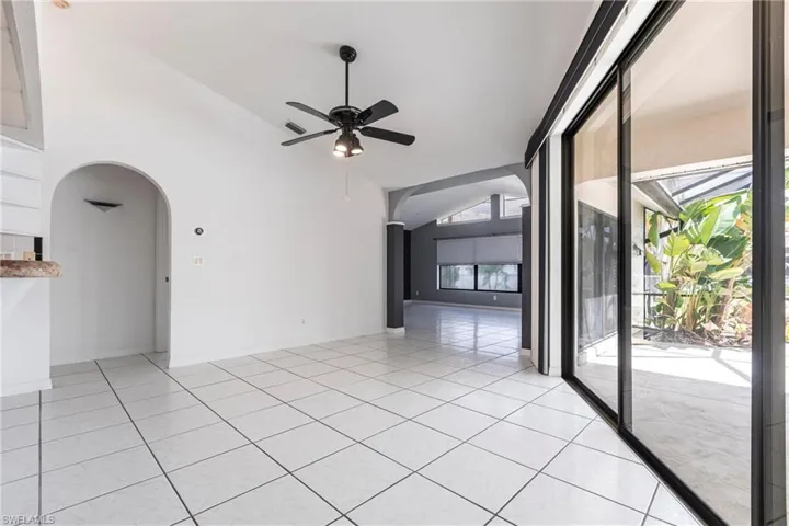 Unfurnished room with arched walkways, vaulted ceiling, a ceiling fan, and light tile patterned floors