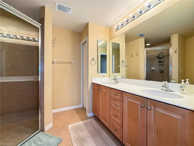 Bathroom with tile patterned flooring, a sink, visible vents, and a shower stall