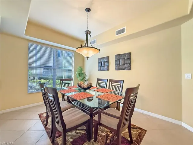 Dining area with light tile patterned floors, visible vents, and baseboards