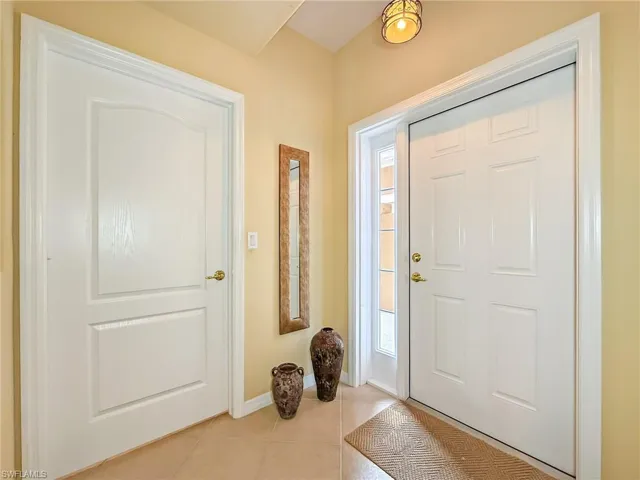 Foyer entrance with light tile patterned flooring and baseboards