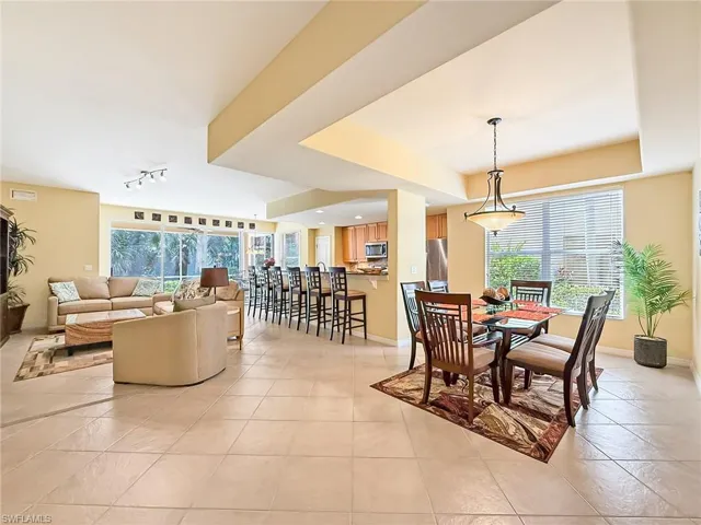 Dining area featuring light tile patterned floors, a tray ceiling, rail lighting, and baseboards