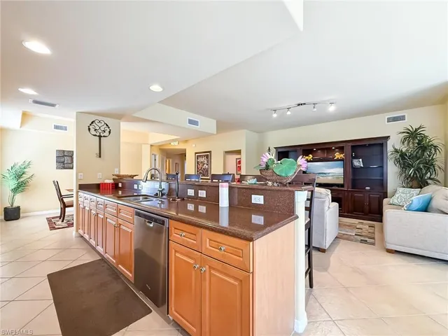 Kitchen with open floor plan, stainless steel dishwasher, a sink, and visible vents