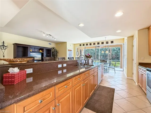 Kitchen with light tile patterned floors, recessed lighting, stainless steel dishwasher, a sink, and dark stone counters