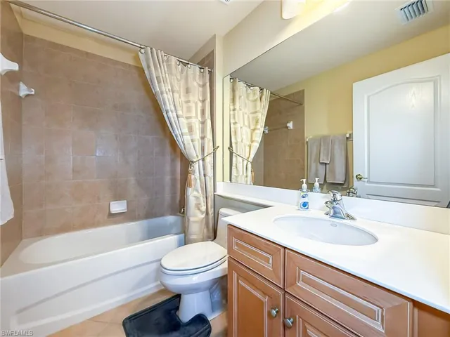 Bathroom with  toilet, shower / bath combo with shower curtain, vanity, and tile patterned flooring