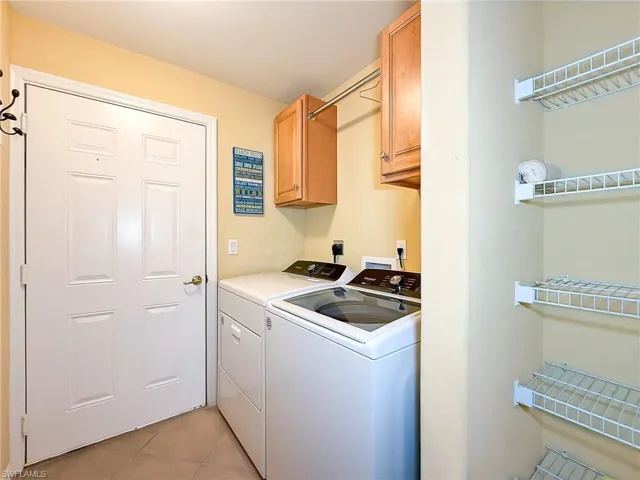 Laundry room featuring light tile patterned floors, cabinet space, and separate washer and dryer