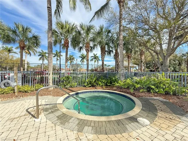 View of pool with a community hot tub and fence