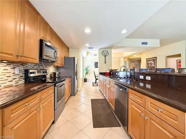 Kitchen with visible vents, backsplash, appliances with stainless steel finishes, light tile patterned flooring, and a sink
