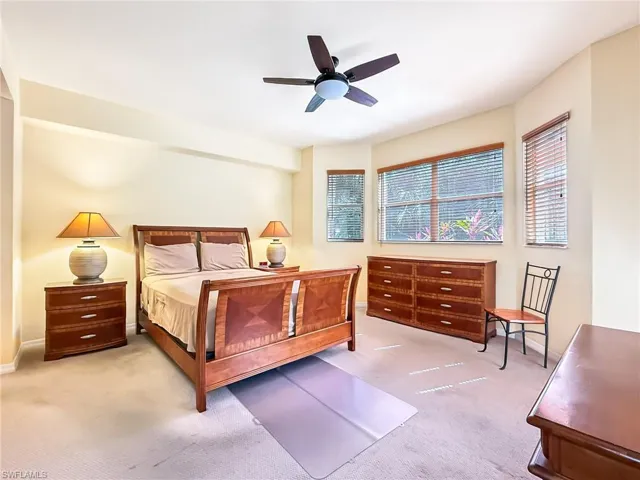 Carpeted bedroom with a ceiling fan and baseboards