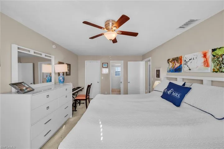 Bedroom with light colored carpet, ceiling fan, and a desk