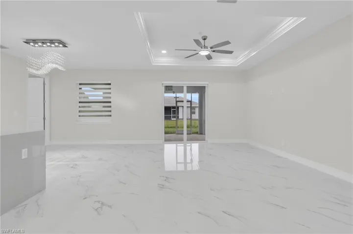 Unfurnished room featuring healthy amount of natural light, ornamental molding, a ceiling fan, and marble finish flooring