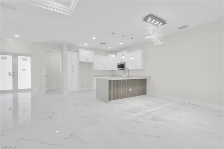 Unfurnished living room featuring recessed lighting, light marble finish flooring, and a chandelier