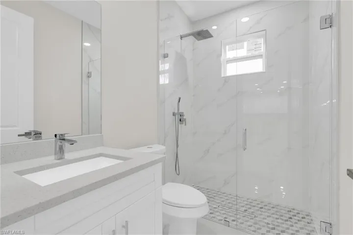 Bathroom with vanity and a marble finish shower