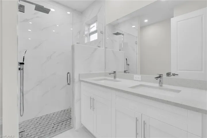 Full bathroom featuring a marble finish shower, double vanity, recessed lighting, and marble finish flooring
