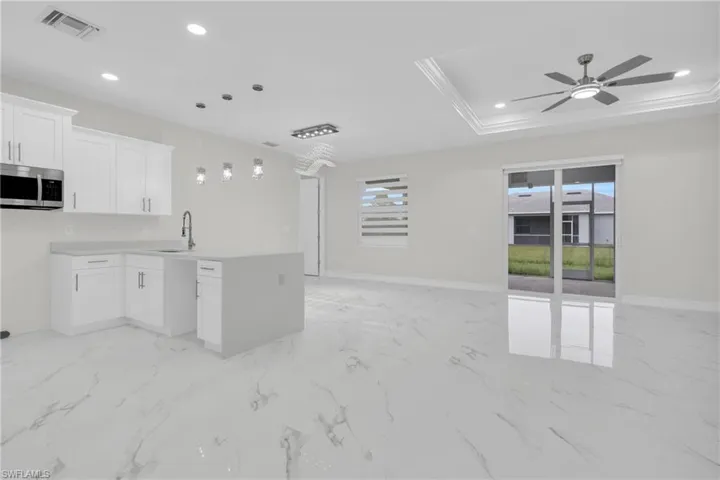 Kitchen featuring stainless steel microwave, open floor plan, a ceiling fan, recessed lighting, and a peninsula