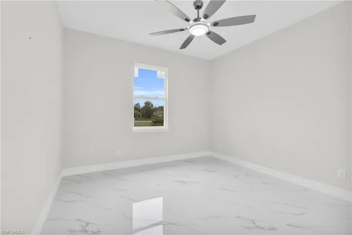 Empty room featuring marble finish floors and a ceiling fan